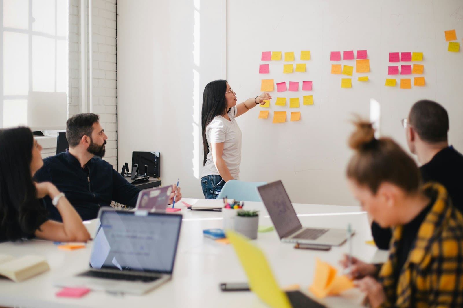 Product workshop with team reviewing sticky notes on a glass wall